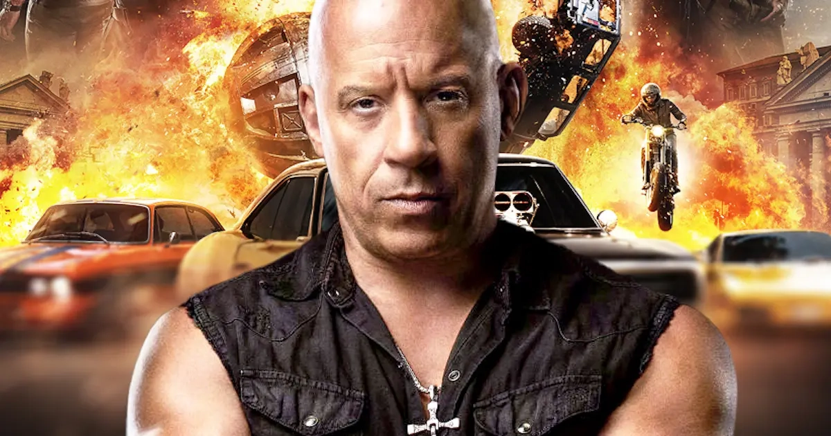 Vin Diesel em evento a promover Fast & Furious 11 com carros de corrida ao fundo